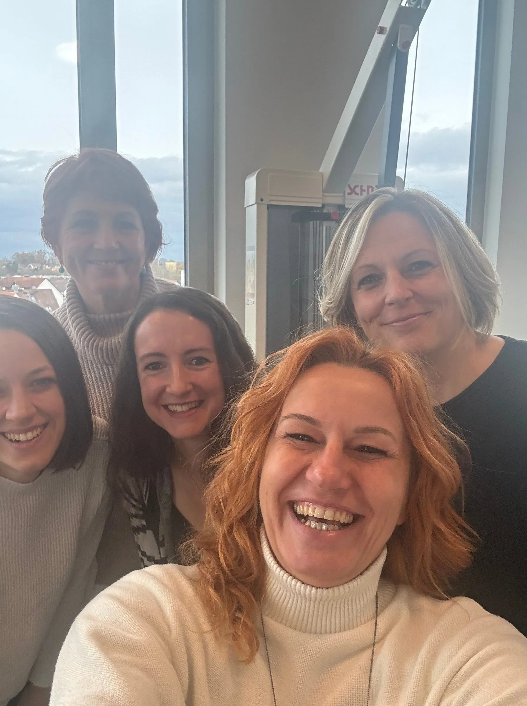 Fünf Frauen aus dem Lenergo-Team beim gemeinsamen Selfie vor großen Fenstern mit Blick über Aichach